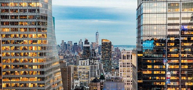 A view of New York City buildings at night with the lights turned on.