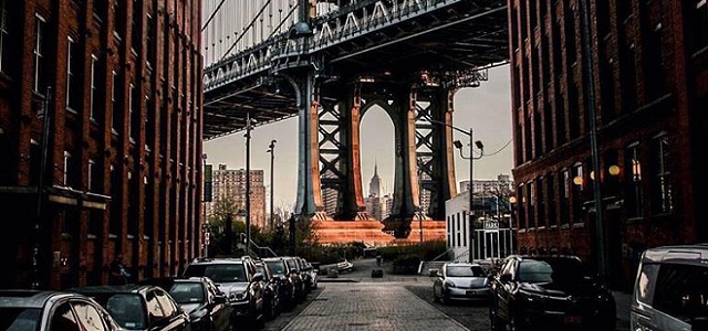 A street view of a bridge connecting NYC as the sun goes down.