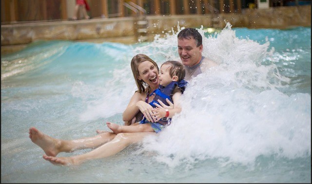 A family playing in the waves of the Slap Tail Pool area at the Wolf Lodge