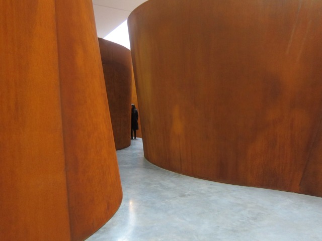Women standing at the end of the winding, narrow pathway between two gigantic, orange steel walls of Richard Seera's exhibition