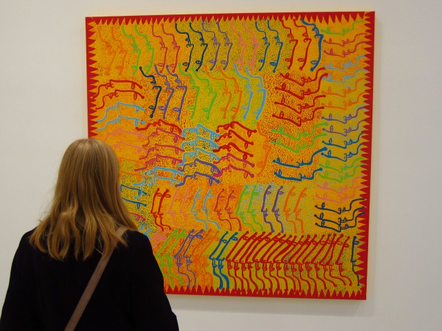 Women admires a brightly colored, abstract painting of artist Yayoi Kusama at David Zwirner
