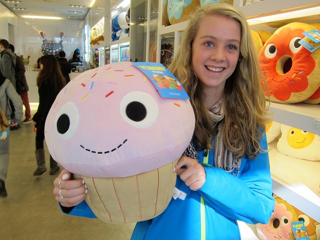 Young girl holding a cup cake stuffed animal with a big smile on her face as she shops for last minute gifts for christmas