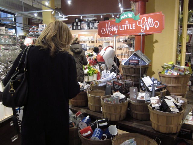 Women looks through the basket of "Merry Little Gifts" at Sur La Table for last minute Christmas stocking stuffers