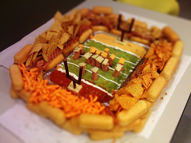 Super bowl snacks stacked up into the shape of a football stadium, using pretzels, dips, pretzels and more