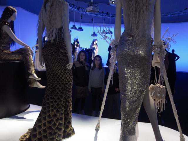 People visiting the Brooklyn museum admiring Jean Paul Gaultier's mannequins dressed up like Mermaids