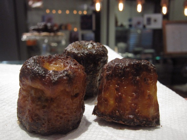 An image of 3 caramel canelés from Canelé by Céline on a napkin.