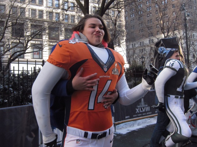 Young women stands behind a mannequin with a Bronco's uniform to take a picture 