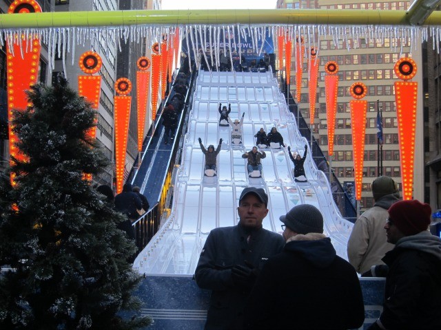 Image of people riding down the huge toboggan now set up in Times Square for Super Bowl Boulevard