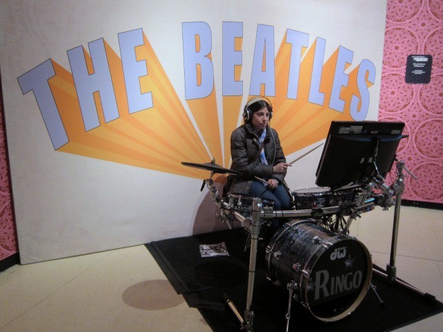 Women at a drum-kit receiving video lessons from Ringo from The Beatles