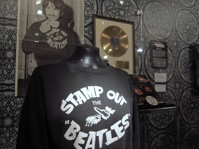 Image of an original black The Beatles t-shirt that says "Stamp Out the Beatles" on display at NYPL