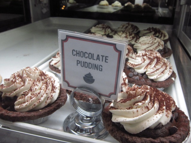 Inside the display case of Hill Country Chicken are a full tray of chocolate pudding pies topped with whipped cream