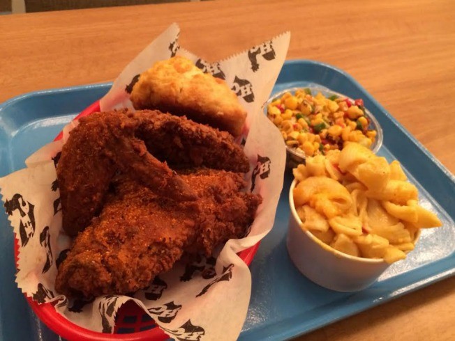 A blue tray filled with barbecue chicken, mac and cheese, corn, and a biscuit from Hill Country Barbecue