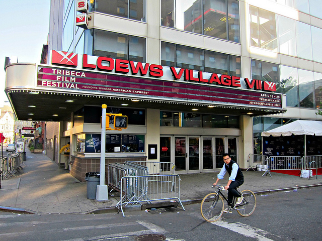 Man on a bike rides past movie theater during Tribeca Film Festival