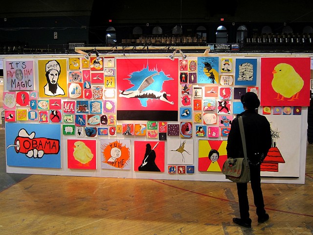 Man standing and admiring a wall of colorful artwork at the Foundation art fair in NYC