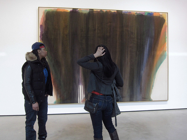 Two women looking at an abstract expressionism painting with mixed colored paint strokes that turned to brown