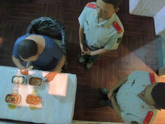 Looking through a tiny window inside one of Ai Weiwei's S.A.C.R.E.D. dioramas, which depicting the artist's life in jail. 