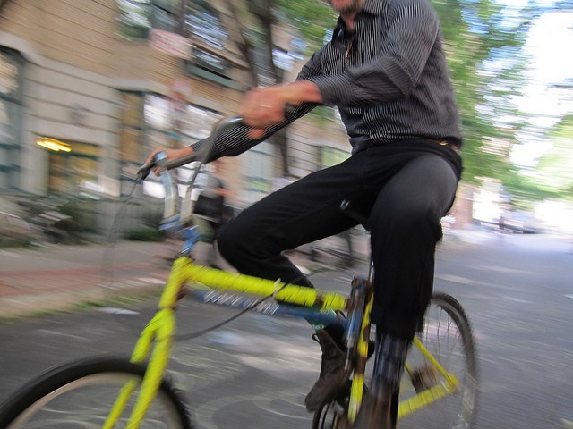 Image of a man riding his bright yellow bicycle through the streets of New York City