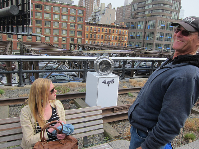 A women sitting at a park bench and a man smiling at The High Line in NYC