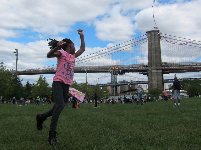 Young girl in pink shirt tries to launch a kit near Brooklyn Bridge