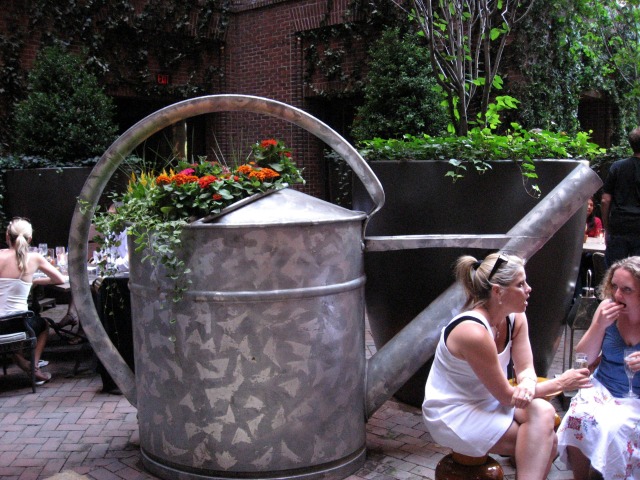 Image of the decor at Hudson Hotel's Rooftop Bar, with a giant watercan as a planter for flowers
