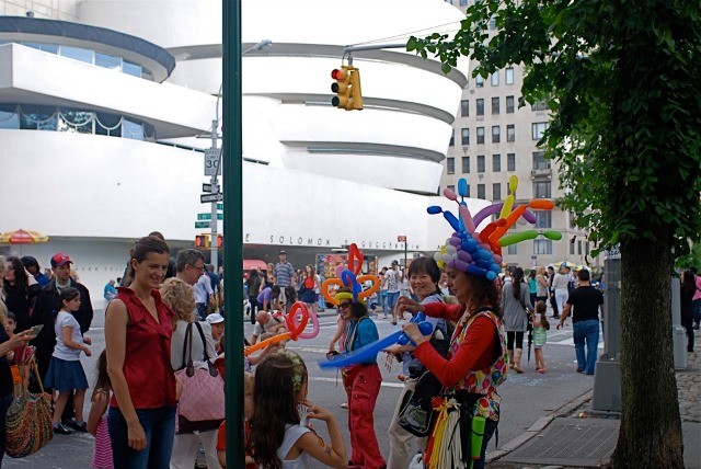 Crowds of people wearing balloon hats and enjoying the festivities of Museum Mile Festival. 