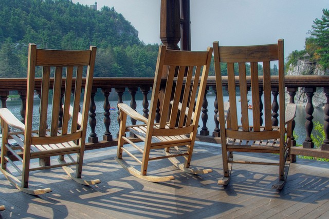 On the porch of Mohonk Mountain House sits three wooden rocking chairs waiting for people to sit in them to enjoy the view