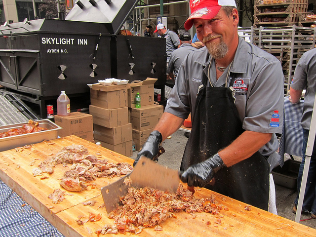 Man working the Big Apple BBQ in NYC by cutting up smoky meat