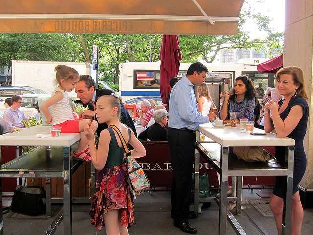 New Yorkers sitting in the counter service area of Epicerie Boulud enjoying their food.