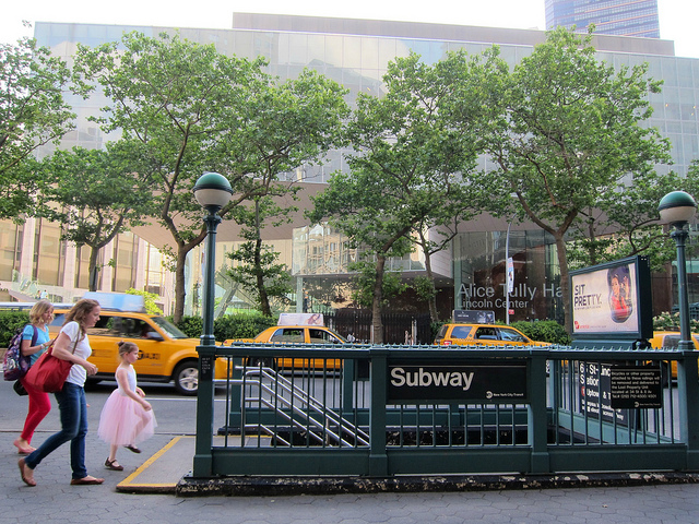 A mother and her daughter walk towards the Lincoln Square subway entrance in NYC.