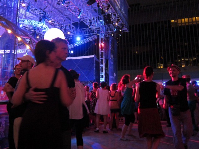 Dimly lit photo of couples dancing by the stage at Lincoln Center