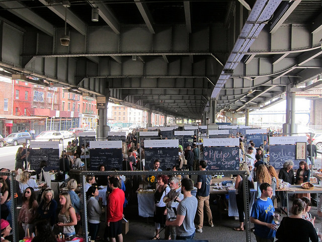 A photo of the New Amsterdam Market from a distance, so you can see all the different vendors set up and crowds walking around.
