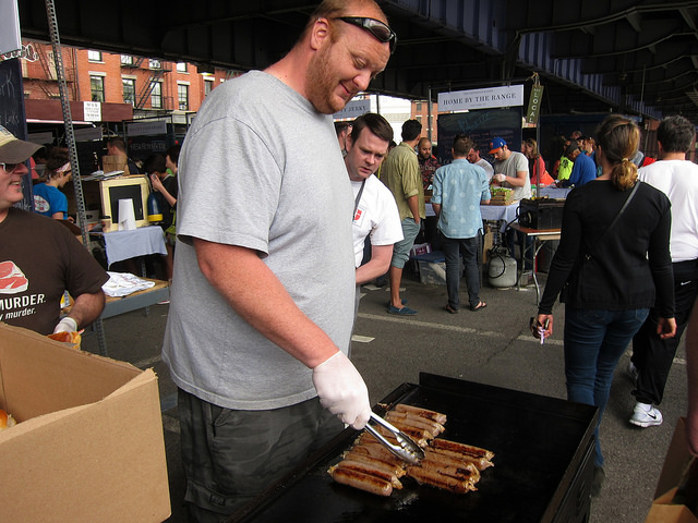 Male employee of Brooklyn Cured, fires up the grill to cook up sausages for customers.