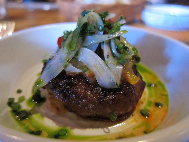 Image of NYC restaurant, Gato's, Chorizo Dish served on a white plate and topped with sauteed onions and basil