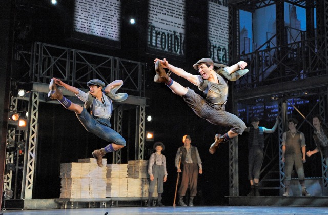 Two actors jump in the air during a performance of Newsies on Boradway in NYC