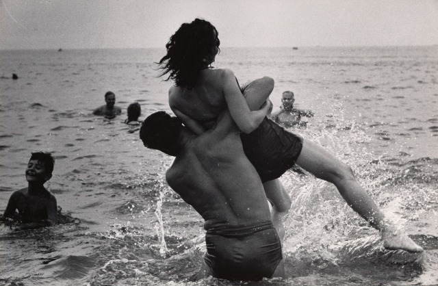 A photograph of a couple playing in the ocean at Coney Island, taken by Garry Winogrand.