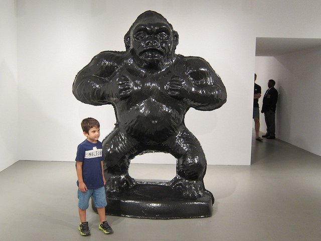 A young boy stands next to a large gorilla sculpture by artist Jeff Koons