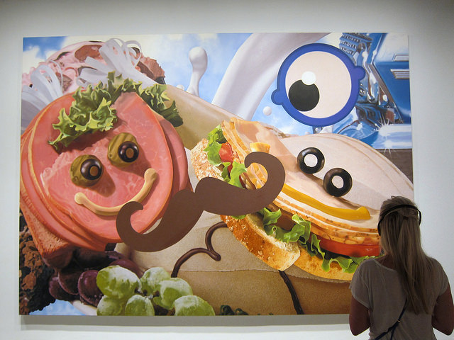 A musuem-goer looking at a piece of Jeff Koons' artwork hanging in the Whitney Museum 