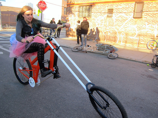 Young women in a tutu rides a large bicycle that looks more like a motorcycle