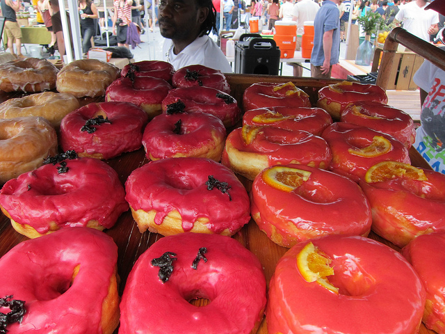 Image of a whole tray of donuts topped with bright pink icings