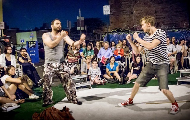 Image of two male actors pretending to fight with a large audience at Shakespeare in a Parking Lot