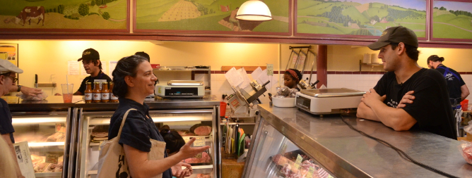 Women walks up to the counter to talk to the butcher about the meat on display