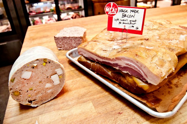 Image of a wooden cutting board with assorted meats on it.