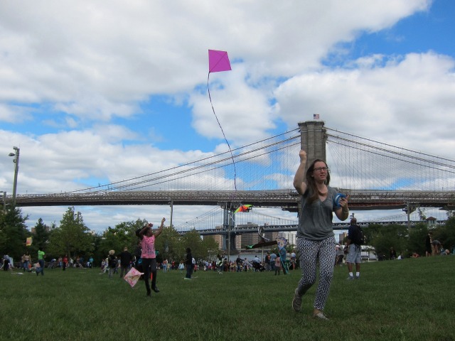 A young kite-flyer enjoys herself with her pink kite at Brooklyn Bridge Park's Kite Festival
