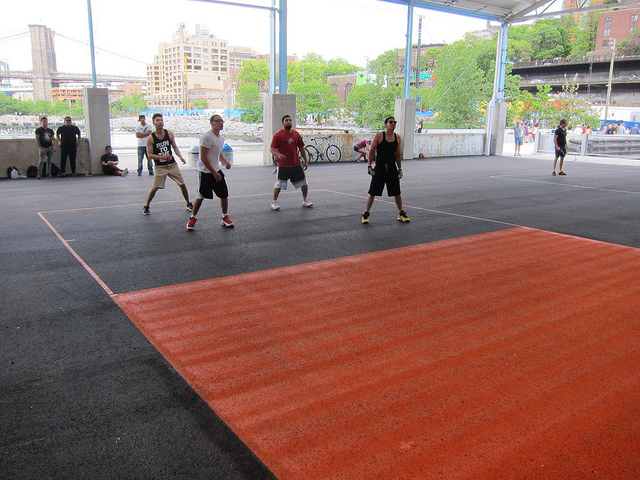 A group of young athletic men play handball on the courts at Pier 2 of the Brooklyn Bridge Park