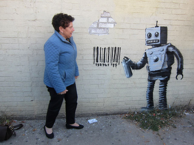 A woman standing in front of a mural made by street artist, Banksy