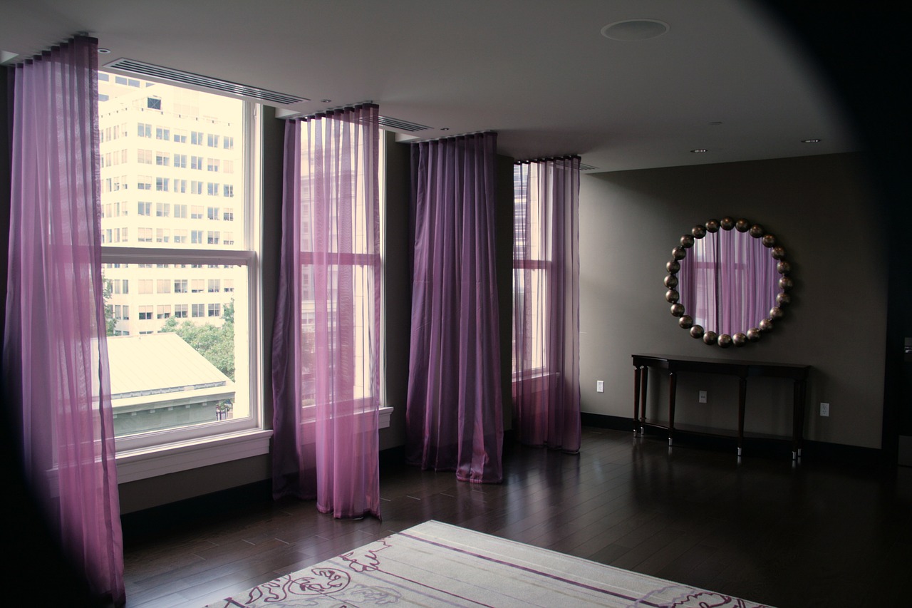 purple curtains open to show a large living room  with a circular mirror at the end