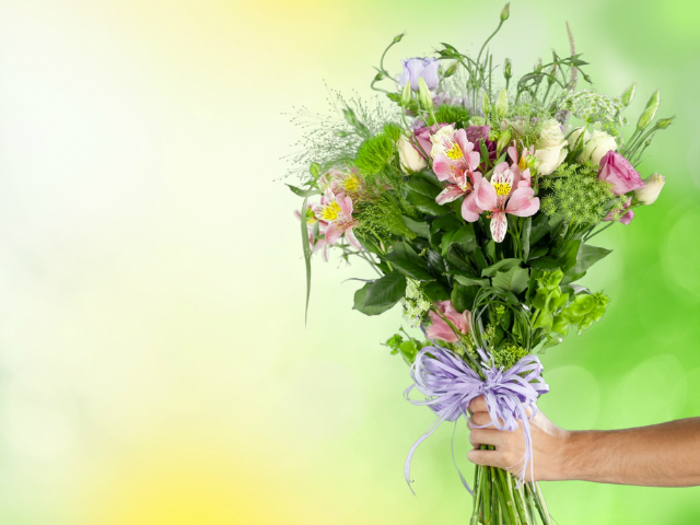 hand holding flower bouquet in front of a yellow and green backdrop