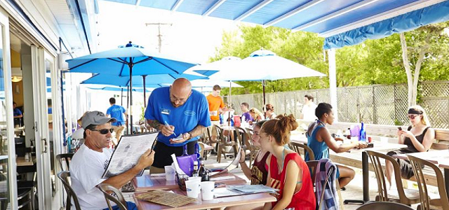 A waiter taking a family's food order at Surf's Out Restaurant outdoor seating area