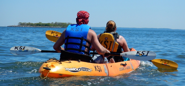 A man and women in an orange kayak from Kayak Staten Island on a sunny day.