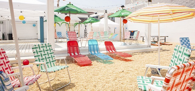 Colorful beach chairs and umbrellas in the sand at the Playland Motel restaurant's outdoor beach area